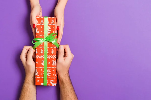 Renkli sırt kaslarının üzerinde kadın ve erkek ellerinde bir hediyenin en üst görüntüsü — Stok fotoğraf