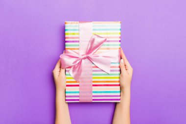 Hediye paketlenmiş ve süslenmiş bir kadın eli uzanıyor. 