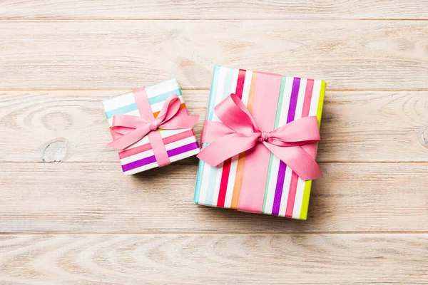 Beautiful gift box with a colored bow on the orange wooden table — Stock Photo, Image