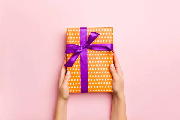 Mani femminili in possesso di scatola regalo a strisce con nastro colorato su l — Foto Stock