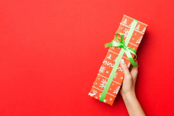 Las manos de la hembra sosteniendo caja de regalo a rayas con cinta de color en r — Foto de Stock