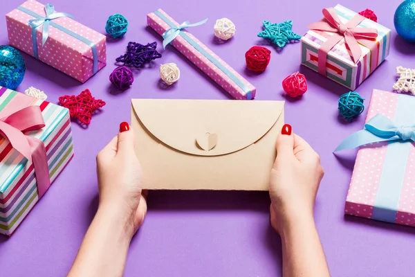 休日の装飾で作られた紫色の背景に封筒を保持する女性のトップビュー。クリスマスタイムコンセプト — ストック写真