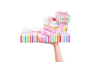 Kadın eli, paketli Noel ya da pembe kurdeleli renkli kağıda sarılı diğer tatil hediyelerini verir. Beyaz arkaplanda izole edilmiş, üst manzara. Şükran Günü hediye kutusu konsepti