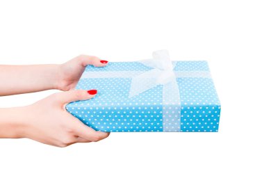 Kadın elleri, beyaz kurdeleli mavi kağıtta paketlenmiş Noel ya da diğer tatil hediyelerini verir. Beyaz arkaplanda izole edilmiş, üst manzara. Şükran Günü hediye kutusu konsepti