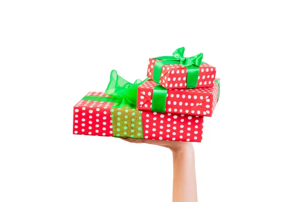 Kadın elleri, yeşil kurdeleli kırmızı kağıtla paketlenmiş Noel veya diğer tatil hediyelerini verir. Beyaz arkaplanda izole edilmiş, üst manzara. Şükran Günü hediye kutusu konsepti — Stok fotoğraf