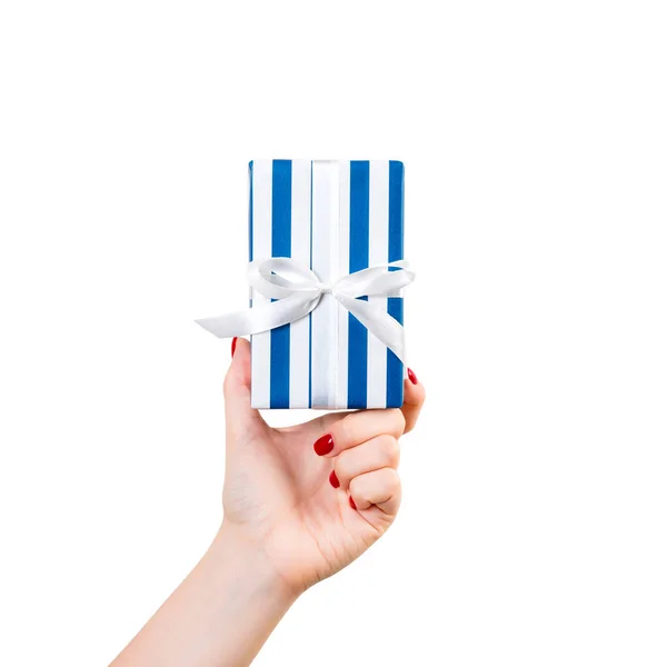 Vrouw handen geven verpakt Kerstmis of andere vakantie met de hand gemaakt in blauw papier met wit lint. Geïsoleerd op witte achtergrond, bovenaanzicht. dankzegging Geschenkdoos concept — Stockfoto
