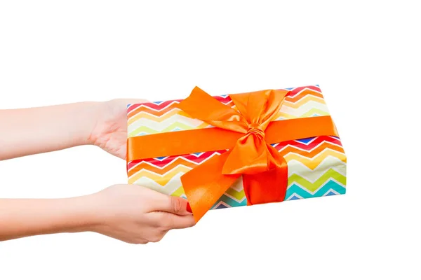 女人的手送给包装好的圣诞节或其他节日手工制作的礼物，礼物用彩色纸和橙色缎带。 独立在白色背景上，顶部视图。 感恩礼盒的概念 — 图库照片