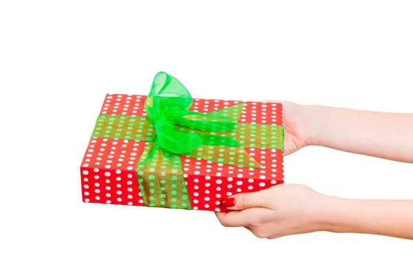 Vrouw handen geven verpakt Kerstmis of andere vakantie met de hand gemaakt in rood papier met groen lint. Geïsoleerd op witte achtergrond, bovenaanzicht. dankzegging Geschenkdoos concept — Stockfoto