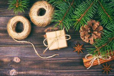 Noel arkaplanı ya da bayram tebrik kartı. Noel hediyesi kutusunda köknar ağacı dalı ve ahşap masa süsleri var. Kopyalama alanı olan üst görünüm. Ayarlanmış