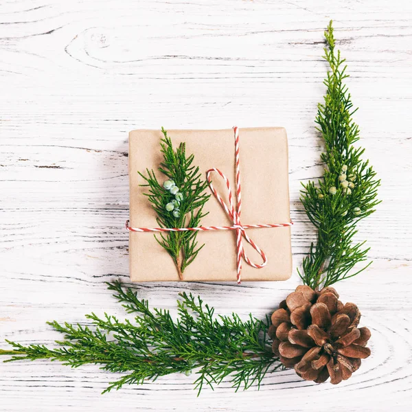 Weihnachten Komposition Hintergrund. Weihnachtsgeschenk mit Tannenzapfen und Tannenzweigen auf Holzgrund. flache Lage, Draufsicht, Kopierraum. gemildert — Stockfoto