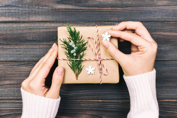 Una mano di donna che tiene la scatola regalo di Natale a portata di mano, su sfondo di legno scuro. vista dall'alto con spazio di copia. Tonica — Foto Stock