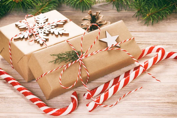 Fir tree branch with christmas gift box and candy canes on wooden background with copy space. Toned — Stock Photo, Image