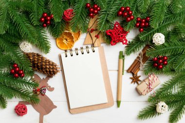 Köknar ağacı dalları, defter ve ahşap arka planda şenlikli dekoratif oyuncaklar. Yeni yıl konsepti