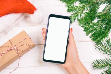Kadın alıcı, akıllı telefon ekranında fotokopi alanı ile sipariş veriyor. Noel alışverişi. Kadınlar Noel için hediyeler alır. Kış tatili satışları. Ayarlanmış