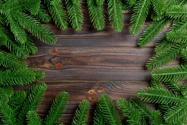 Κάτοψη του πλαισίου από κλαδιά ελάτης σε ξύλινο φόντο. Χριστουγεννιάτικη ιδέα με κενό χώρο για το σχεδιασμό σας — Φωτογραφία Αρχείου