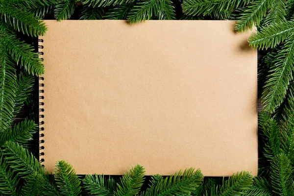 Ahşap zemin üzerinde köknar ağacından yapılmış bir çerçeve ile dekore edilmiş el işi kağıdından yapılmış defterin üst görüntüsü. Yeni yıl konsepti — Stok fotoğraf