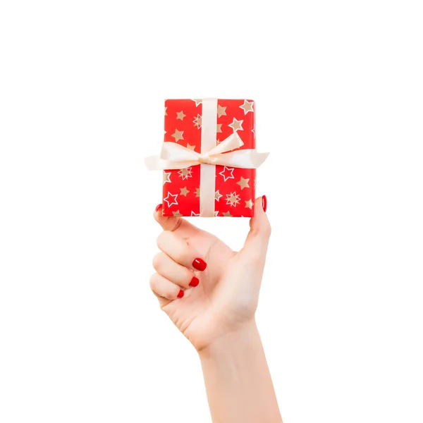 女性の手は金リボンと赤い紙に包まれたクリスマスや他の休日の手作りプレゼントを与える。白い背景に、上部のビューに隔離された。感謝祭のギフトボックスコンセプト — ストック写真