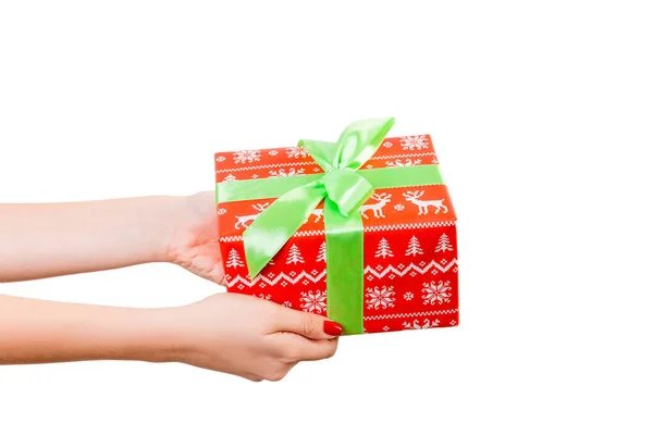 Kobiece dłonie dają zawinięte Boże Narodzenie lub inne świąteczne ręcznie robione prezenty w czerwony papier z zieloną wstążką. Izolacja na białym tle, widok z góry. dziękczynienie koncepcja pudełko prezent — Zdjęcie stockowe
