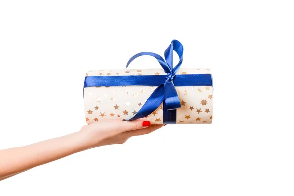 女人的手送给包装好的圣诞节或其他节日手工制作的礼物，礼物用金纸和蓝丝带。 独立在白色背景上，顶部视图。 感恩礼盒的概念 — 图库照片