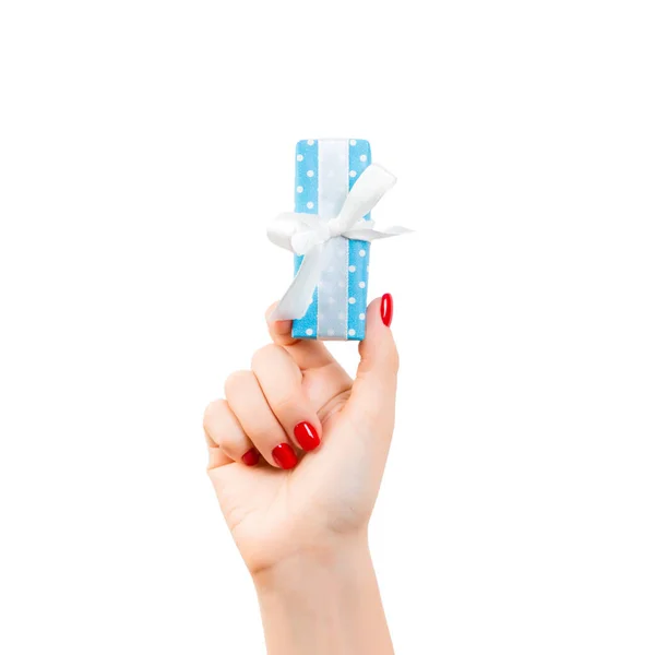 Женские руки подарят завернутое Рождество или другой праздник ручной работы в голубой бумаге с белой лентой. Изолированный на белом фоне, вид сверху. Подарочная коробка — стоковое фото
