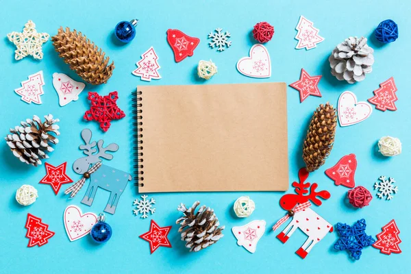 Bovenaanzicht van notebook omgeven met Nieuwjaar speelgoed en decoraties op blauwe achtergrond. Kerstconcept — Stockfoto