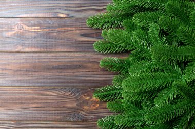 Ahşap zemin üzerinde köknar ağacı dallarından yapılmış çerçevenin üst görüntüsü. Tasarımınız için boş boşluklu Noel kavramı