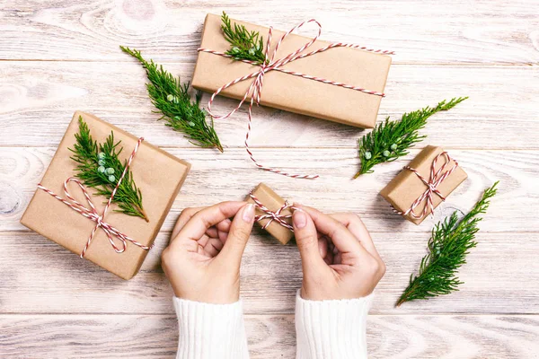 Frauenhände, die flachen Hintergrund für Neujahrs- oder Weihnachtsgeschenke halten. Vorlage Feiertagsfeier handgemachte Geschenkschachtel und Tannenzapfen Draufsicht. gemildert — Stockfoto