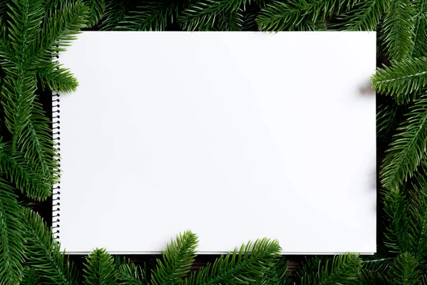 Ahşap zemin üzerinde köknar ağacından yapılmış bir çerçeve ile dekore edilmiş defter üst görünümü. Yeni yıl konsepti — Stok fotoğraf