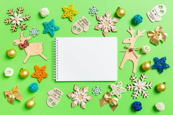 Bovenaanzicht van notebook op groene achtergrond met nieuwjaarsspeelgoed en decoraties. Kerstconcept — Stockfoto