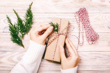 Yeni Yıl 'ı ya da Noel' i kucaklayan kadın eller düz arka planda yatıyordu. Noel kutlaması el yapımı hediye kutusu ve köknar ağacı konileri. Ayarlanmış