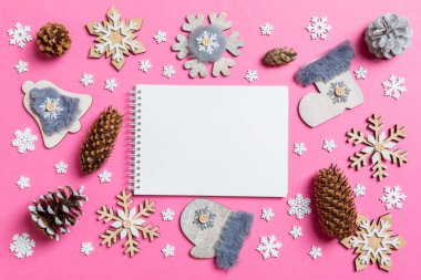 Not defterinin üst görüntüsü, tatil oyuncakları ve pembe Noel arkaplanındaki süslemeler. Yeni yıl konsepti