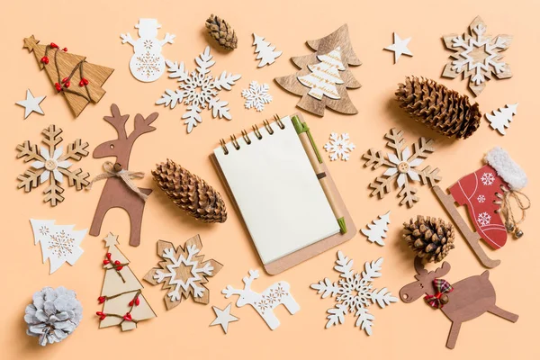 Top view of notebook surrounded with New Year toys and decorations on orange background. Christmas time concept — Stock Photo, Image