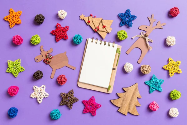 Bovenaanzicht van het notitieboek. Nieuwjaar decoraties op paarse achtergrond. Feestelijke sterren en ballen. Vrolijk kerstconcept — Stockfoto