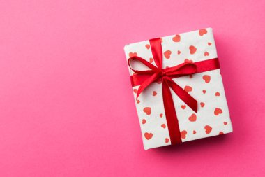 Arkaplanda hediye kutusu ve pembe arka planda kalpler var. Metin için kopyalama alanı olan üst görünüm