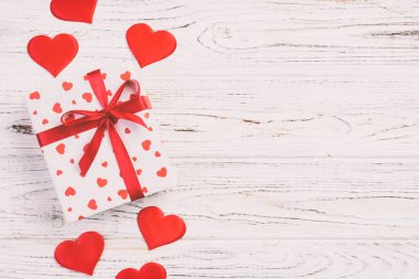 Sevgililer veya diğer tatil el yapımı mevcut kağıt ile tatil sarmalayıcı kırmızı kalpler ve hediye kutusunda. Tasarım için kopya alanı görünümüyle Beyaz ahşap masa üstü, boş alanı hediye kutusu