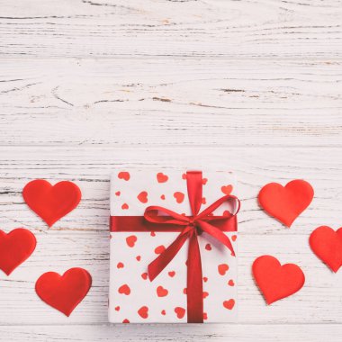 Sevgililer veya diğer tatil el yapımı mevcut kağıt ile tatil sarmalayıcı kırmızı kalpler ve hediye kutusunda. Tasarım için kopya alanı görünümüyle Beyaz ahşap masa üstü, boş alanı hediye kutusu