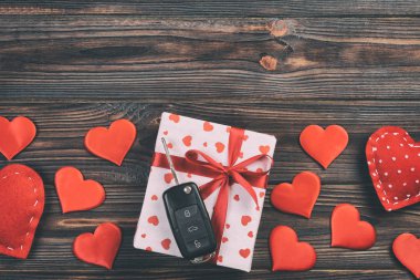 Sevgililer günü ya da diğer tatil hediyeleri kırmızı kalpler, araba anahtarları ve tatil ambalajında hediye paketi. Koyu ahşap masa üstü görünümlü kutu hediyesi kopyalama alanı, tasarım için boş alan