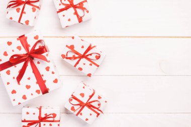 Sevgililer veya diğer tatil el yapımı mevcut kağıt ile tatil sarmalayıcı kırmızı kalpler ve hediye kutusunda. Tasarım için kopya alanı görünümüyle Beyaz ahşap masa üstü, boş alanı kutusu hediye sunmak