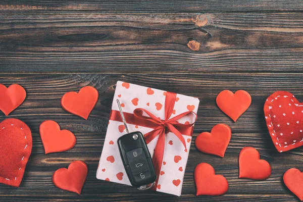 Sevgililer günü ya da diğer tatil hediyeleri kırmızı kalpler, araba anahtarları ve tatil ambalajında hediye paketi. Koyu ahşap masa üstü görünümlü kutu hediyesi kopyalama alanı, tasarım için boş alan