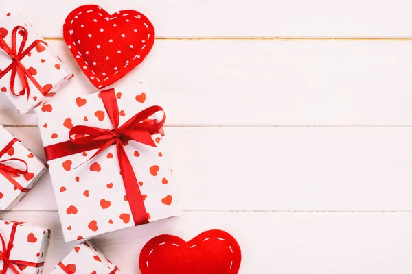 San Valentín u otro regalo hecho a mano en papel con corazones rojos y caja de regalos en envoltorio de vacaciones. Regalo de la caja presente en la vista superior de la mesa de madera con espacio de copia, espacio vacío para el diseño — Foto de Stock