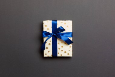 Noel 'i ya da diğer tatil hediyelerini siyah arka planda mavi kurdeleli kağıda sardım. Şimdiki kutu, renkli tabloda hediye süslemesi, kopya alanı ile üst görünüm