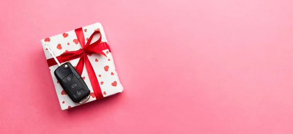 Kluczyk na papier pudełko z kokardą czerwoną wstążką i serca na tle różowy stół. Wakacje przedstawić koncepcję widok z góry — Zdjęcie stockowe