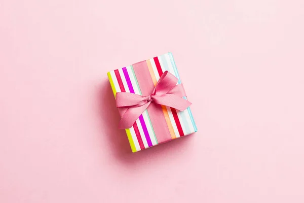 Envuelto Navidad u otro regalo hecho a mano de vacaciones en papel con cinta rosa sobre fondo rosa. Caja de regalo, decoración de regalo en mesa de colores, vista superior con espacio para copiar — Foto de Stock