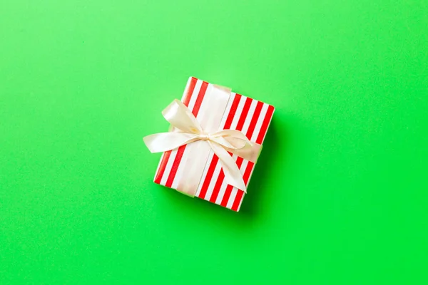 Τυλιγμένο Χριστούγεννα ή άλλες διακοπές χειροποίητο δώρο σε χαρτί με κίτρινη κορδέλα σε πράσινο φόντο. Παρουσιάστε το κιβώτιο, διακόσμηση του δώρου στο χρωματιστό τραπέζι, top view με το διάστημα αντιγράφων — Φωτογραφία Αρχείου