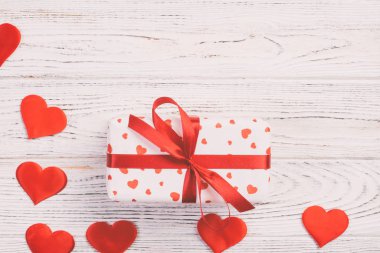 Sevgililer veya diğer tatil el yapımı mevcut kağıt ile tatil sarmalayıcı kırmızı kalpler ve hediye kutusunda. Tasarım için kopya alanı görünümüyle Beyaz ahşap masa üstü, boş alanı hediye kutusu