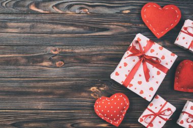 Sevgililer veya diğer tatil el yapımı mevcut kağıt ile tatil sarmalayıcı kırmızı kalpler ve hediye kutusunda. Tasarım için kopya alanı görünümüyle koyu ahşap masa üstü, boş alanı hediye kutusu