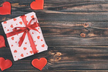 Sevgililer veya diğer tatil el yapımı mevcut kağıt ile tatil sarmalayıcı kırmızı kalpler ve hediye kutusunda. Tasarım için kopya alanı görünümüyle koyu ahşap masa üstü, boş alanı hediye kutusu