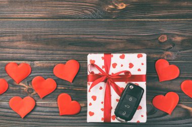 Sevgililer günü ya da diğer tatil hediyeleri kırmızı kalpler, araba anahtarları ve tatil ambalajında hediye paketi. Koyu ahşap masa üstü görünümlü kutu hediyesi kopyalama alanı, tasarım için boş alan