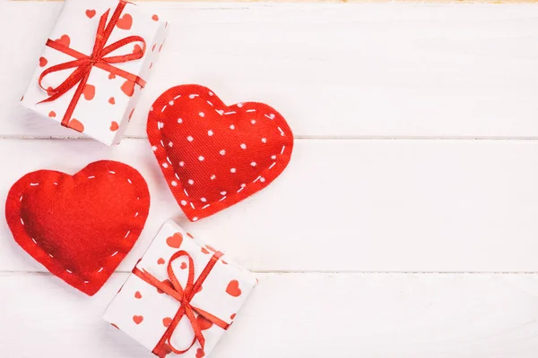 San Valentín u otro regalo hecho a mano en papel con corazones rojos y caja de regalos en envoltorio de vacaciones. Regalo de caja de regalo en vista superior de mesa de madera blanca con espacio de copia, espacio vacío para el diseño — Foto de Stock