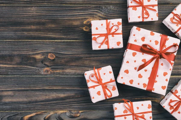 San Valentín u otro regalo hecho a mano en papel con corazones rojos y caja de regalos en envoltorio de vacaciones. Presente caja de regalo en la vista superior de madera oscura mesa con espacio para copiar, espacio vacío para el diseño —  Fotos de Stock